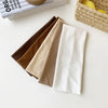 A stack of five brown, beige, and white elastic hairbands for fitness and yoga placed next to a book.