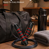 A black adjustable weighted speed jump rope is displayed next to a gym bag and a towel.
