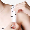 A hand is applying clear double-sided fashion tape with black polka dots to a piece of clothing.