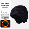 A dark navy knitted winter hat with a pom-pom, designed for warmth and ear protection.