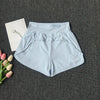 Light blue women's high-waist yoga and fitness shorts laid flat on a dark gray surface next to pink and white flowers.