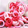 Haufen bunter rosa und roter Nylon-Haargummis für Pferdeschwänze und Zöpfe.