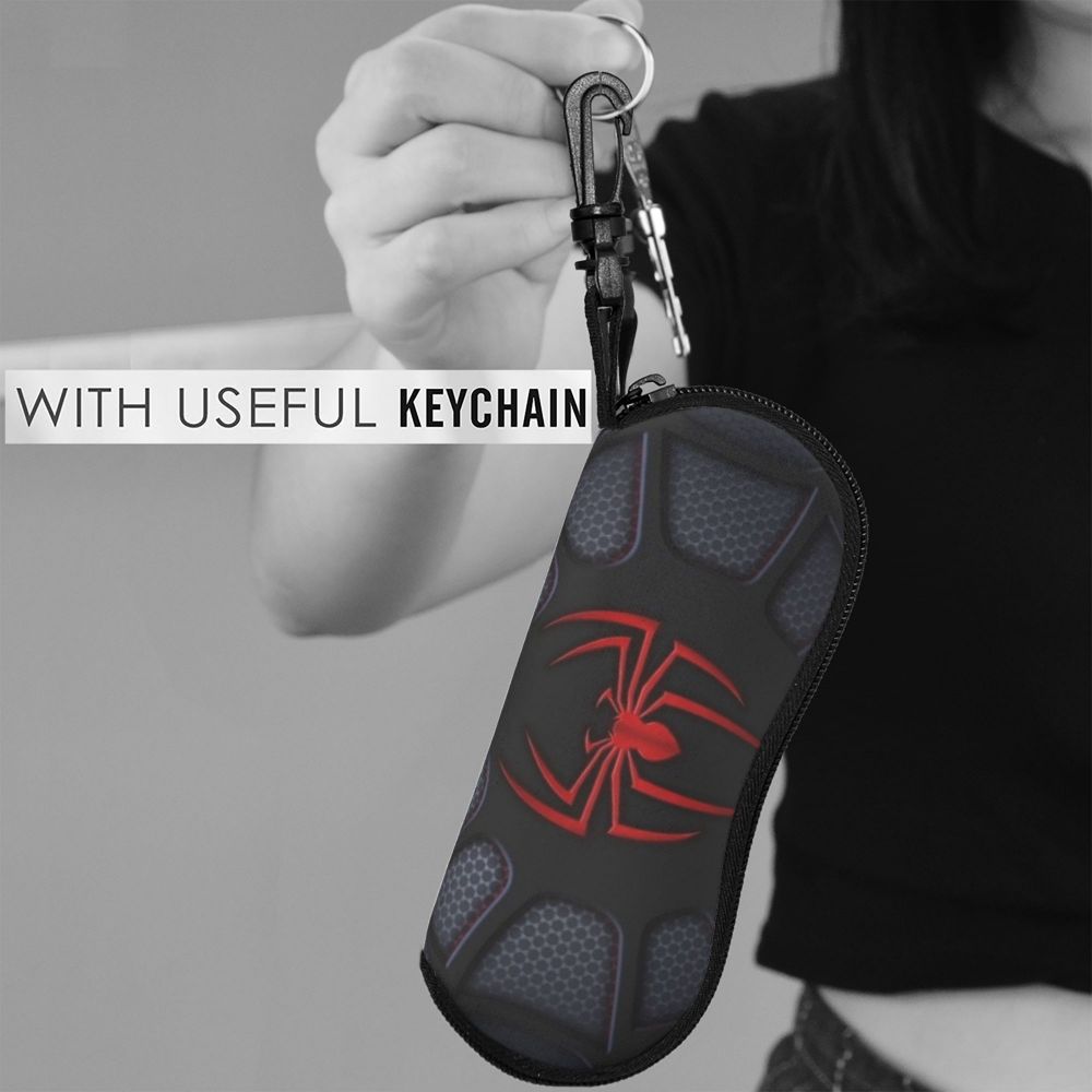 A black silicone pouch featuring a red spider web design is being held by a hand with a keychain attached.