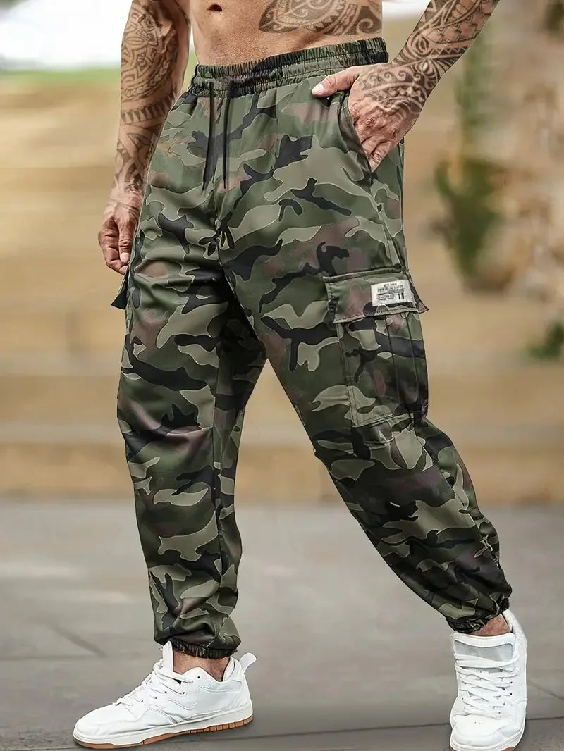 Un homme portant un pantalon cargo camouflage et des baskets blanches, montrant la coupe du pantalon.