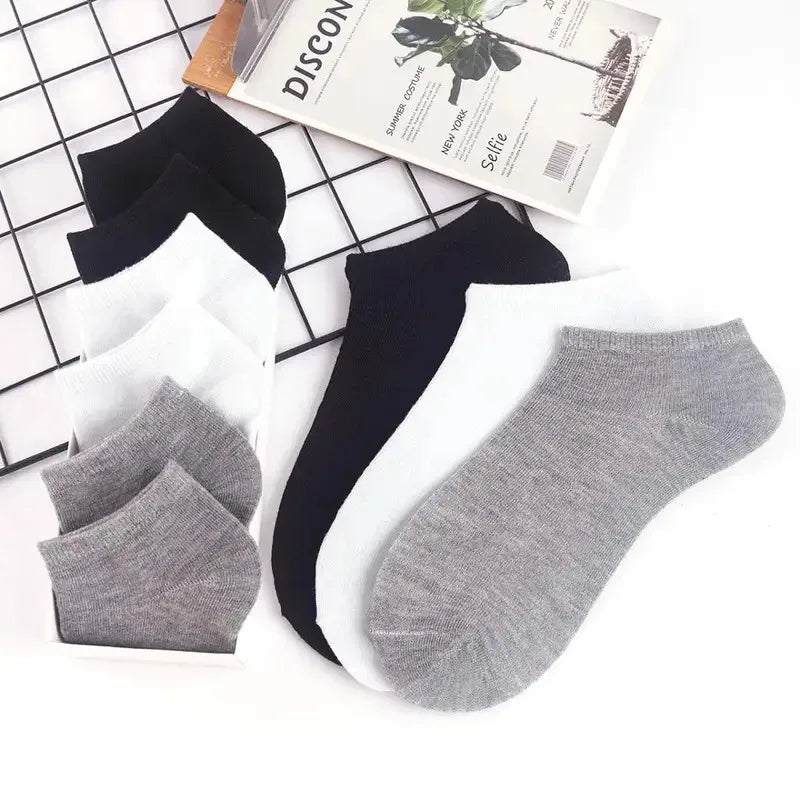 Una colección de calcetines de tobillo negros, blancos y grises junto a un folleto de descuento.