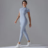 A model wearing a light blue Naked Zipper Yoga Jumpsuit standing against a gray background.