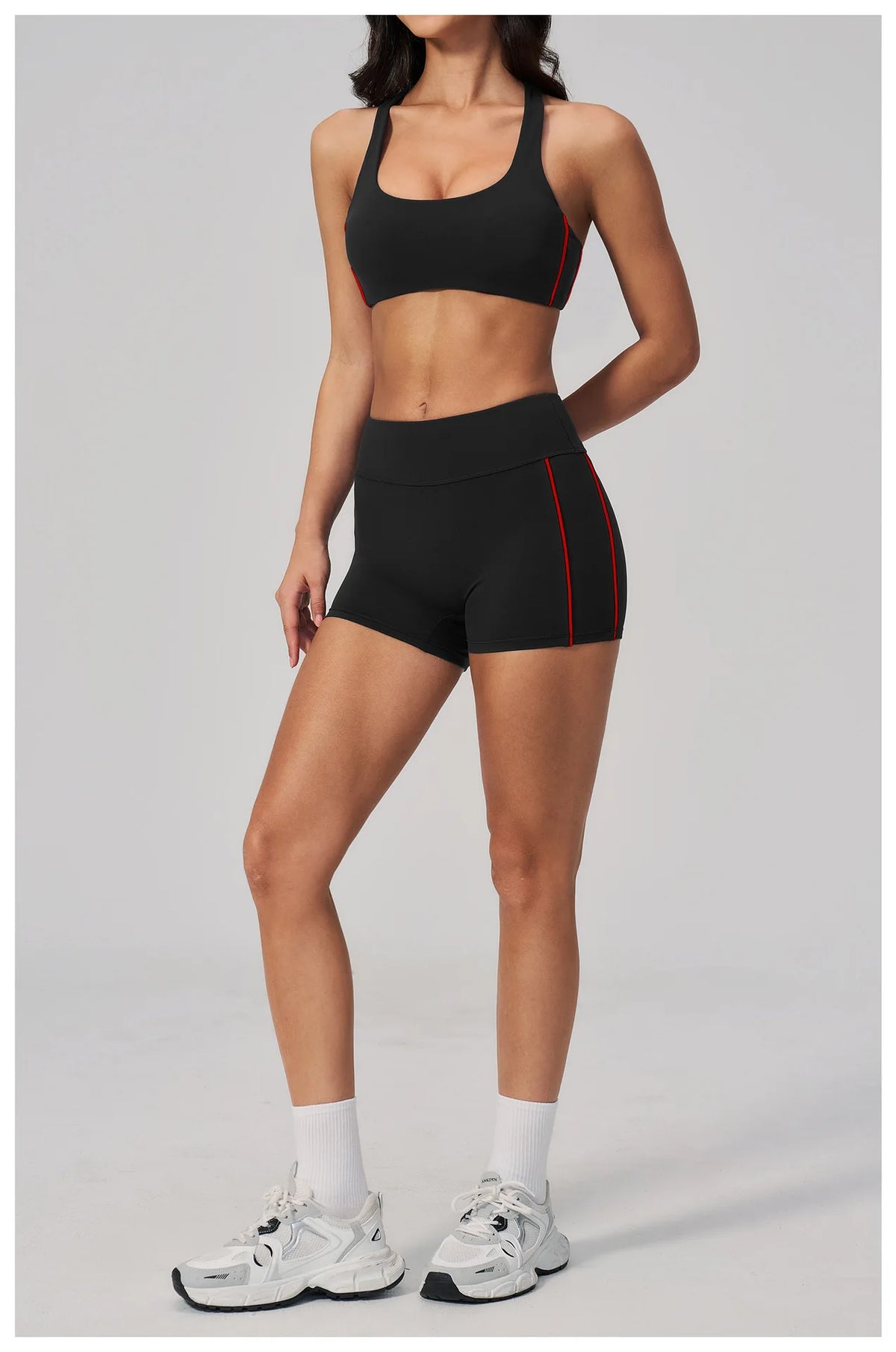 A woman models a black two-piece yoga and sports tracksuit set with red accents.
