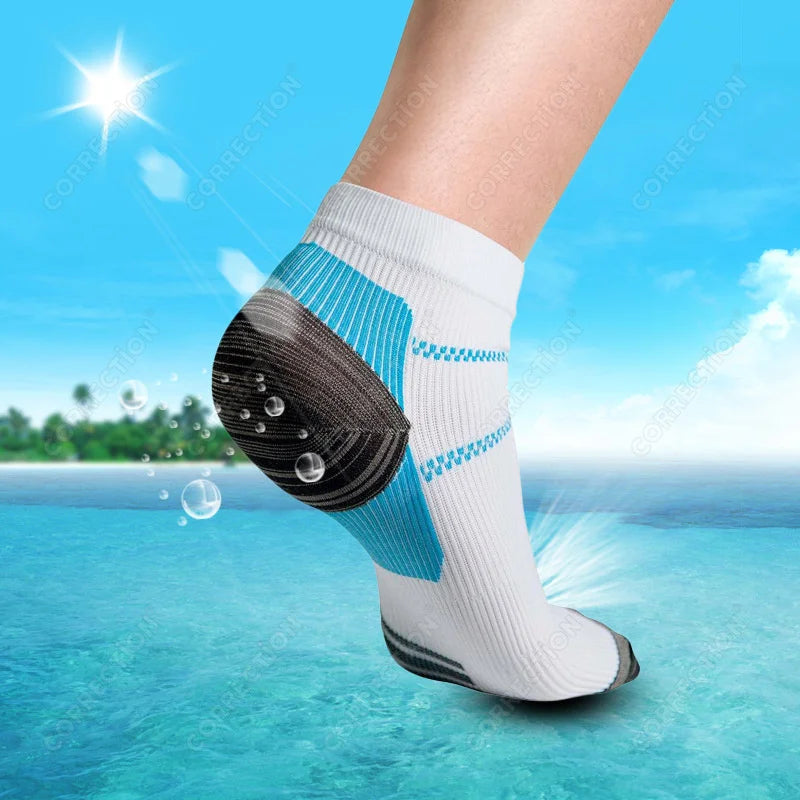 A close-up of white compression socks with blue accents and a black sole, shown on a person's foot against a bright blue wate
