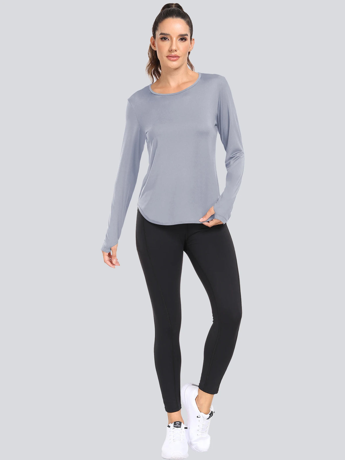 A woman models a light gray loose fit long-sleeve t-shirt and black leggings.