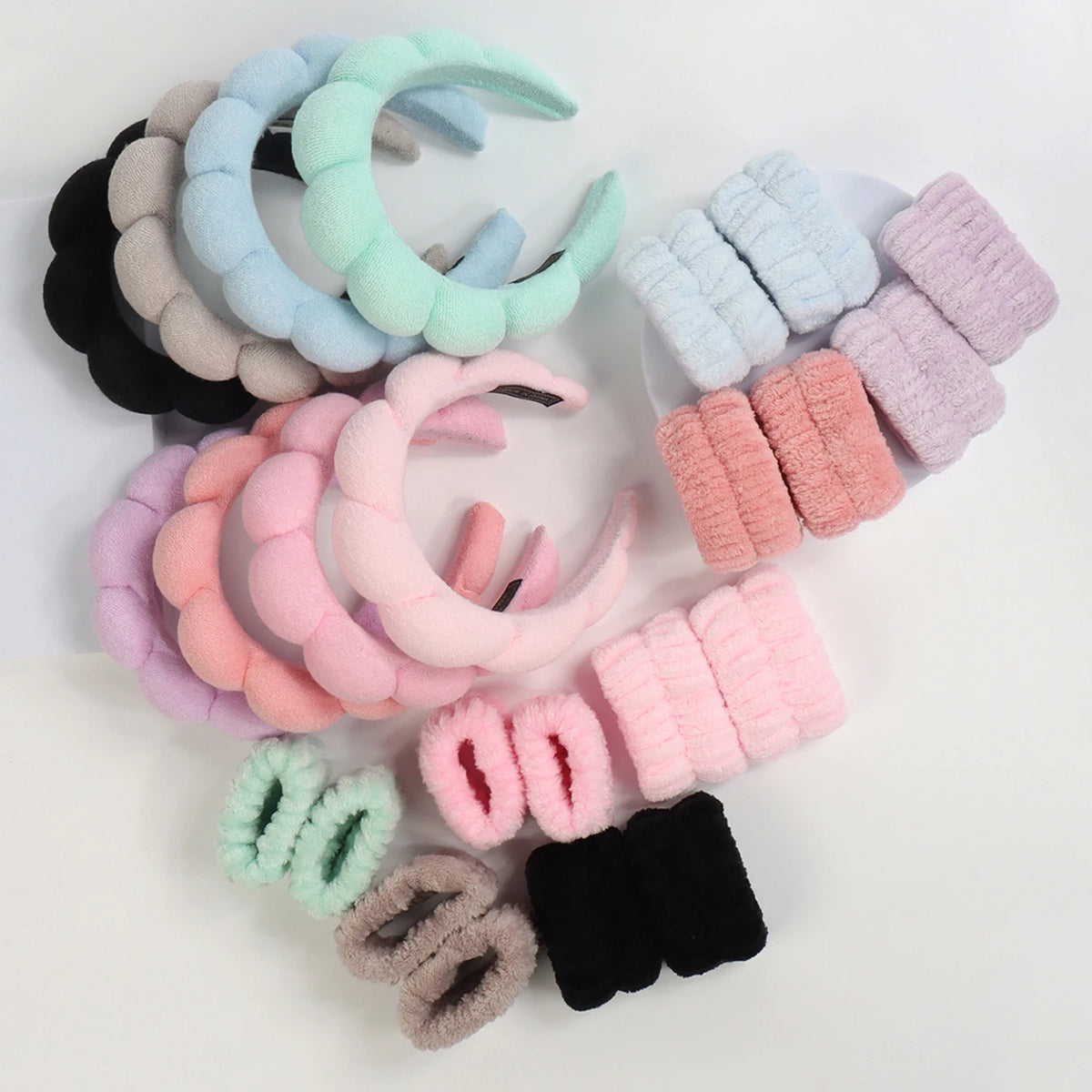 A collection of colorful microfiber skincare headbands and wristbands in pastel shades.