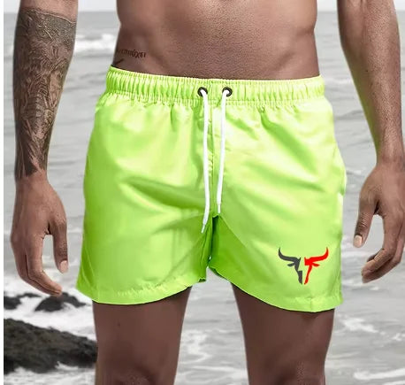 Lime green quick-drying men's swim shorts worn by a person standing near the water.