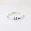 A white silicone wristband with the number 23 printed on it.