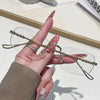 A hand holds a pair of thin, gold-toned frameless rectangle glasses with clear lenses.