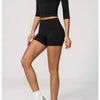A woman models a black long-sleeved top and matching high-waisted shorts set of yoga and fitness leggings.