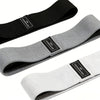 Three fabric resistance bands in black, gray, and white shown diagonally.