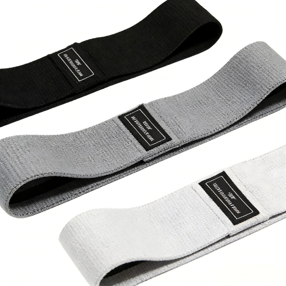 Three fabric resistance bands in black, gray, and white shown diagonally.