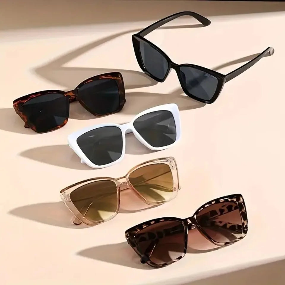 A collection of vintage cat eye sunglasses in black, brown, and gold gradient lenses displayed on a light background.