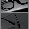 A close-up of retro black anti-blue light glasses resting on a dark surface.