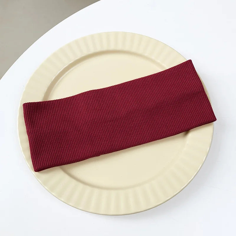 A maroon elastic hairband is placed diagonally across a light beige plate.