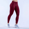 A person wearing maroon high-waisted seamless yoga leggings and light gray athletic shoes.