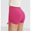 A model is wearing bright pink performance yoga shorts with a drawstring waist.