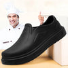 A black men's anti-slip oil-resistant kitchen clog is shown next to a chef and a white block.
