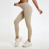 A model wearing beige high-waist yoga leggings and white athletic shoes.