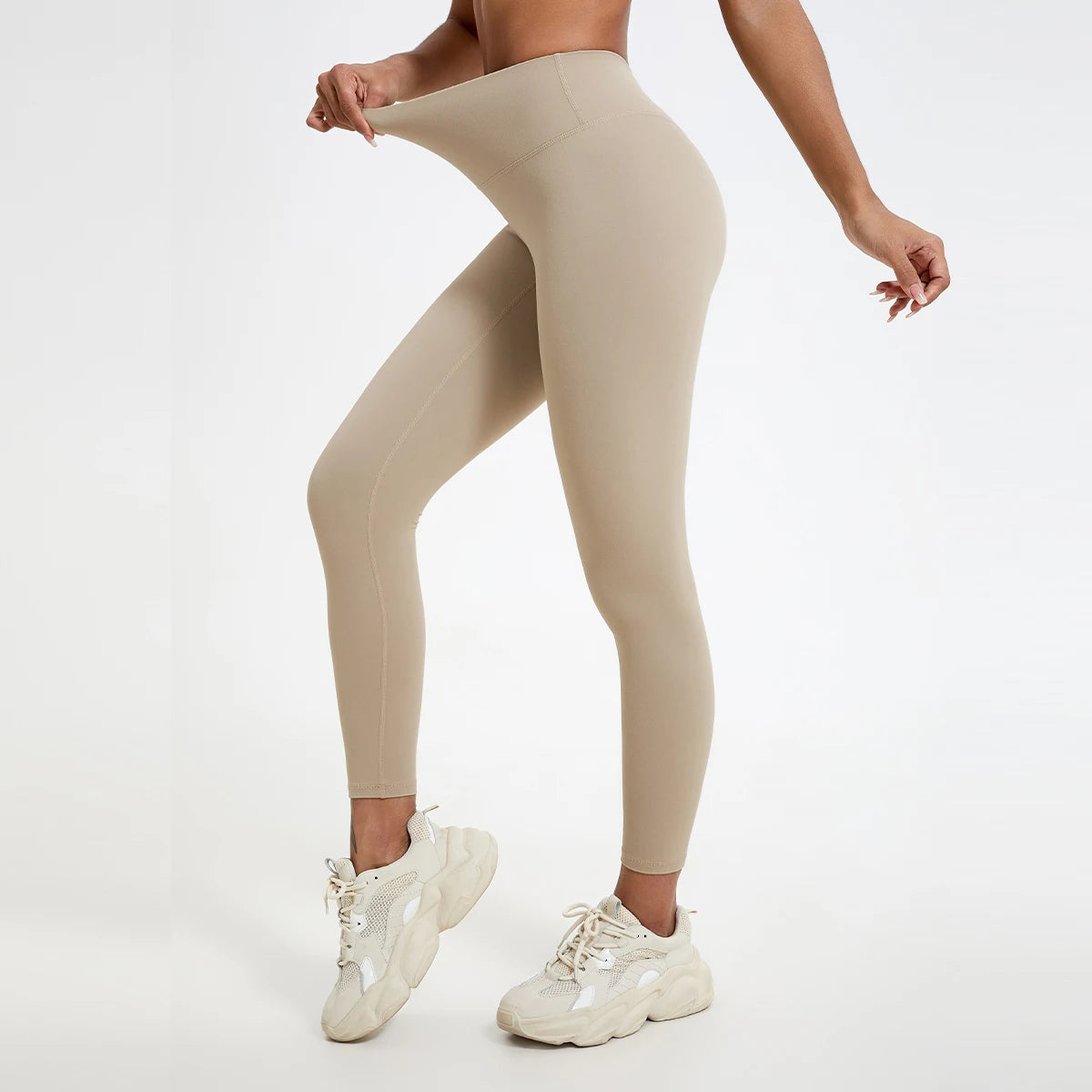 A model wearing beige high-waist yoga leggings and white athletic shoes.