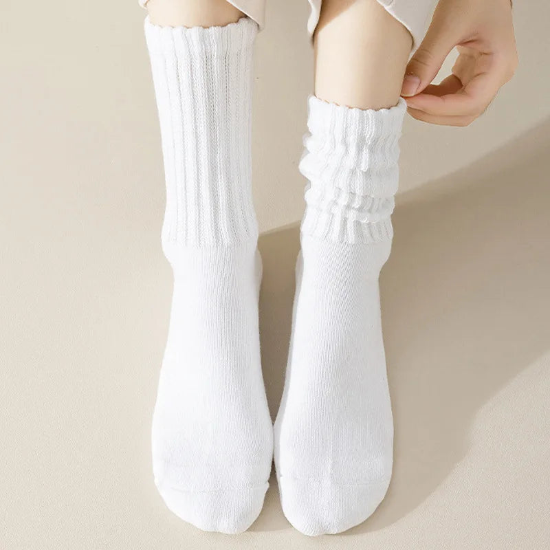 Un par de calcetines de punto blancos siendo puestos en el tobillo y el pie de una persona.