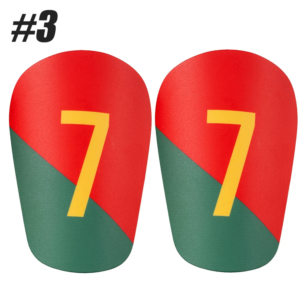 A pair of red soccer shin guards with yellow numbers 77 on a green background.