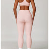 A woman models a pink three-piece yoga sports set consisting of a crop top, leggings, and sports bra.