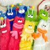A collection of funny plush caterpillar floor socks in various bright colors like pink, blue, green, and yellow.