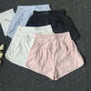 A collection of women's high-waist yoga and fitness shorts in various colors including light blue, black, and pink, laid out 