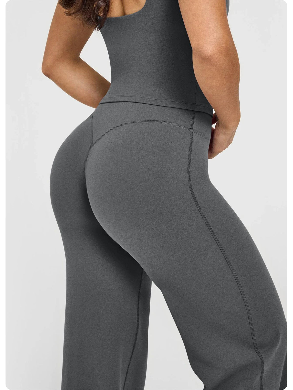 A woman wearing high waisted wide leg yoga pants in a solid gray color.