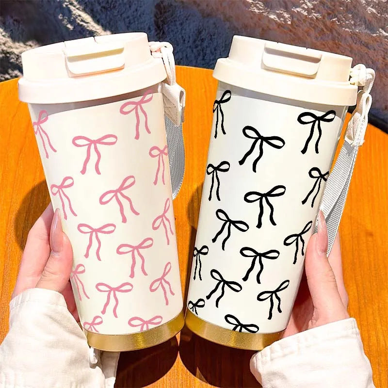 A hand holds a white and pink patterned double-wall insulated stainless steel travel mug.