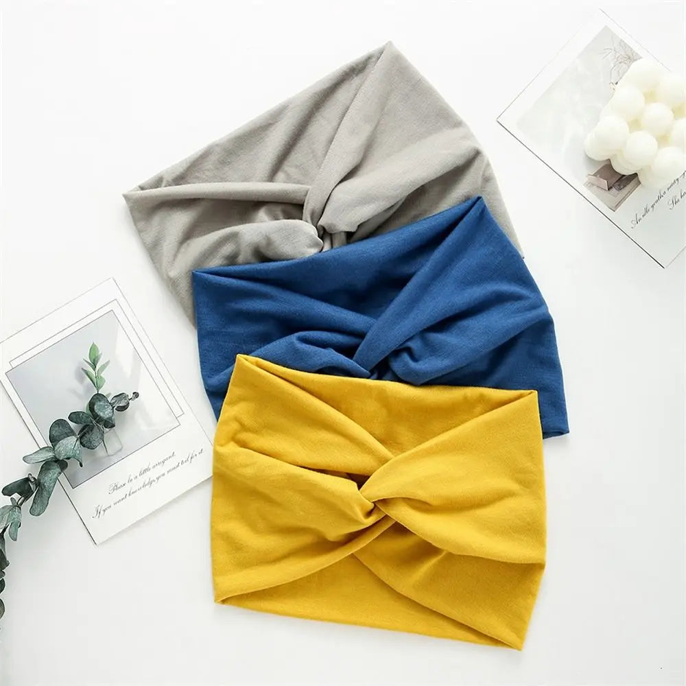 Une pile de bandeaux pour les cheveux en tissu bohème tressé gris, bleu et jaune sur fond blanc.