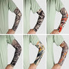 A set of full arm tattoo sleeves in black and orange designs worn on the arms of a person.