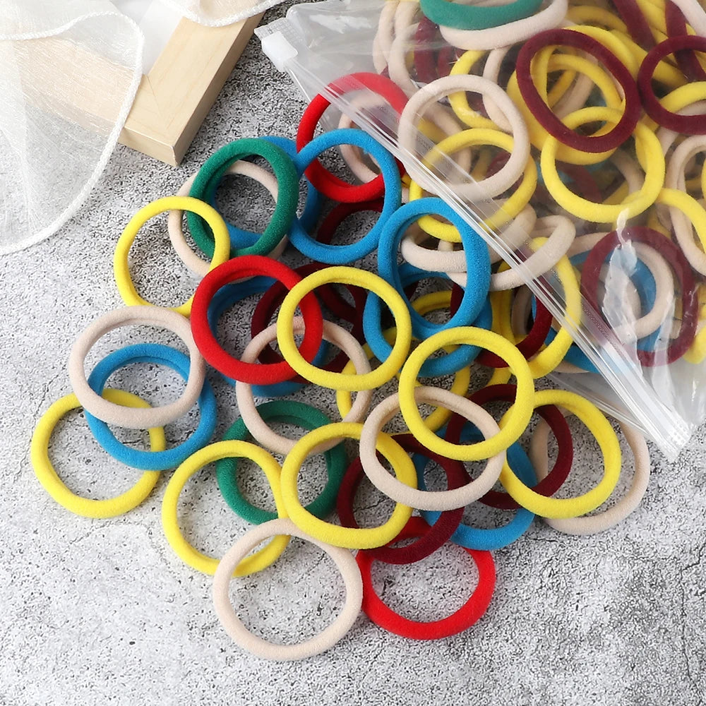 A pile of 50 mixed color elastic hair bands in various shades of red, yellow, green, and blue.