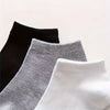 A stack of black, gray, and white ankle socks displayed against a white background.