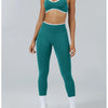 A woman models teal high-waist yoga leggings with white trim and white socks.
