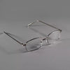 A pair of clear, retro square frame eyeglasses resting on a gray surface.