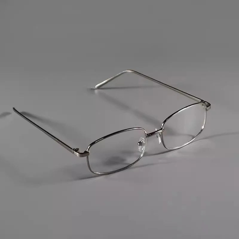 A pair of clear, retro square frame eyeglasses resting on a gray surface.