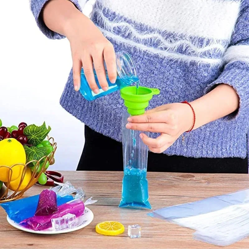 Una persona está vertiendo líquido azul en una bolsa molde para paletas de hielo verde sobre una mesa de madera.