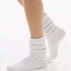 White slouch knit scrunch socks worn on a leg.