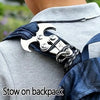 A stainless steel folding grappling hook is attached to a dark blue fabric strap, positioned on a light gray jacket.