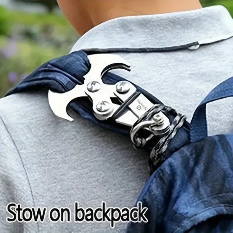 A stainless steel folding grappling hook is attached to a dark blue fabric strap, positioned on a light gray jacket.