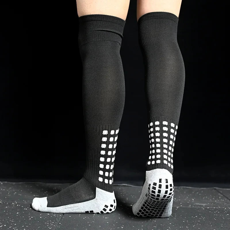 A pair of black long football training socks with a white patterned toe and heel.
