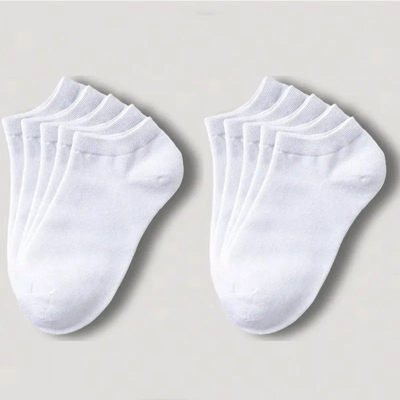 Una pila de calcetines de algodón transpirables unisex blancos de tobillo, dispuestos sobre una superficie clara.