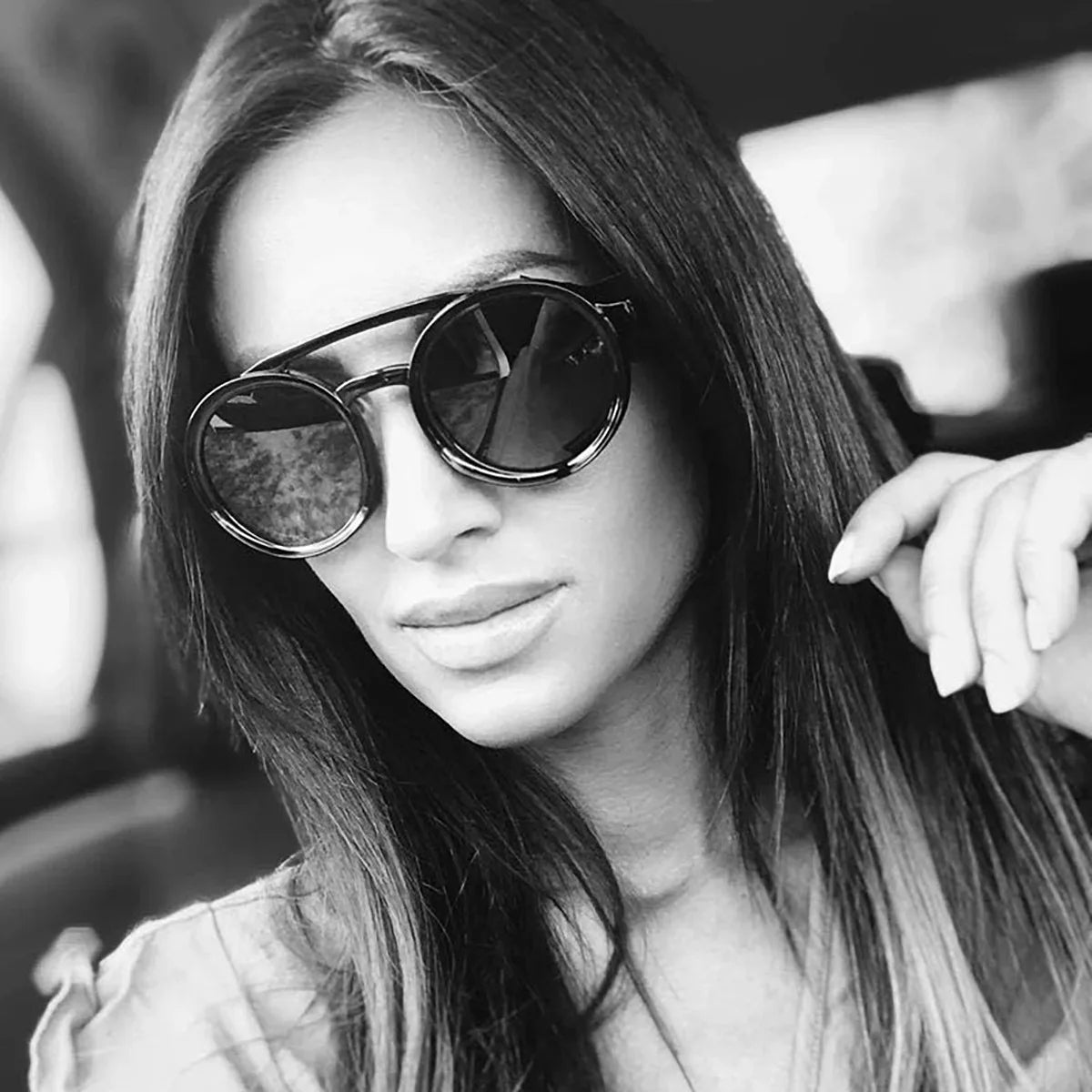 Close-up portrait of a woman wearing round, dark-lensed retro steampunk style sunglasses.