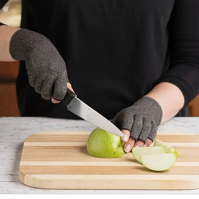 A person wearing dark gloves is slicing an apple on a wooden cutting board.
